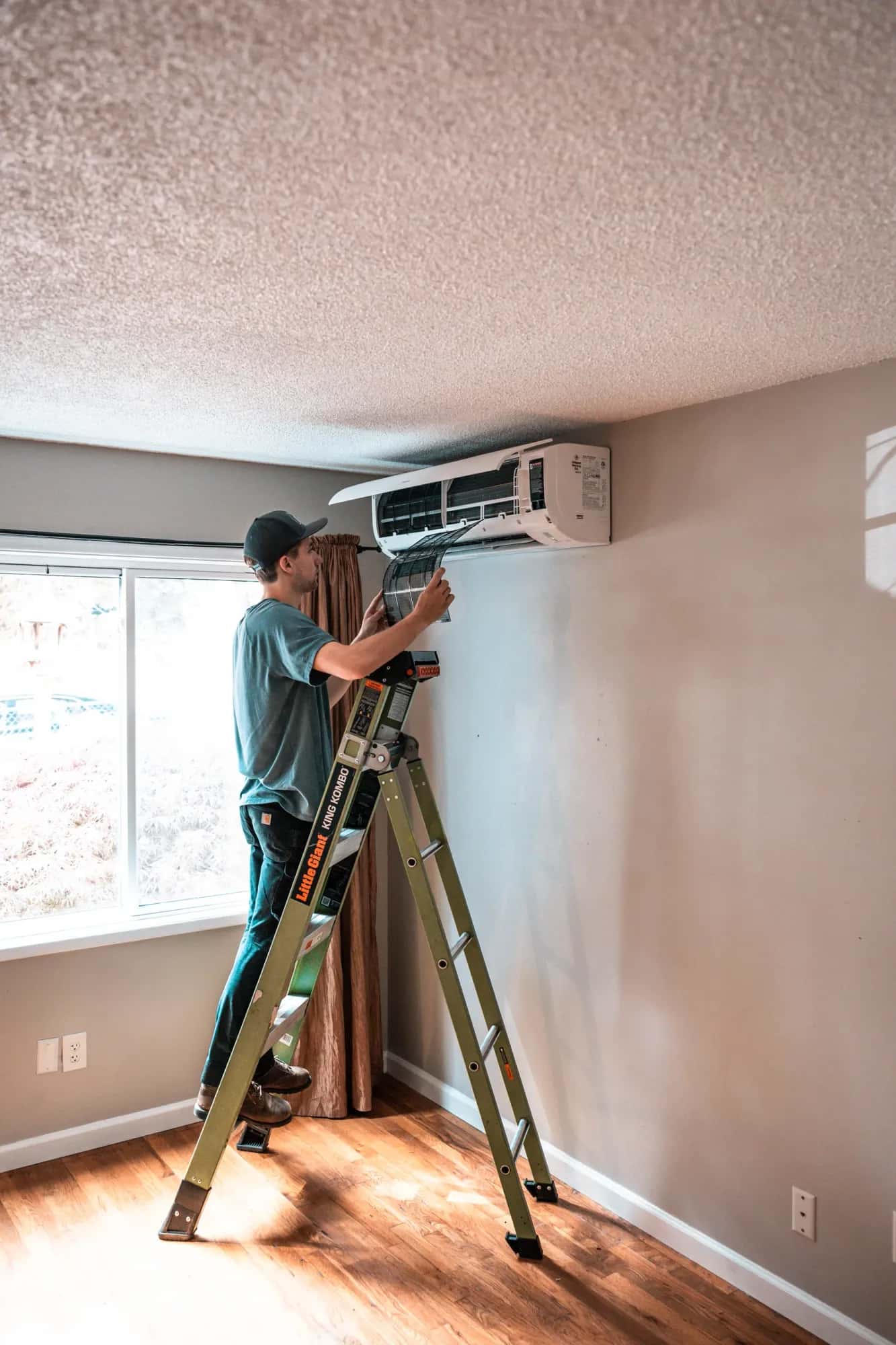 Ed installing an indoor ductless mini-split unit from a ladder